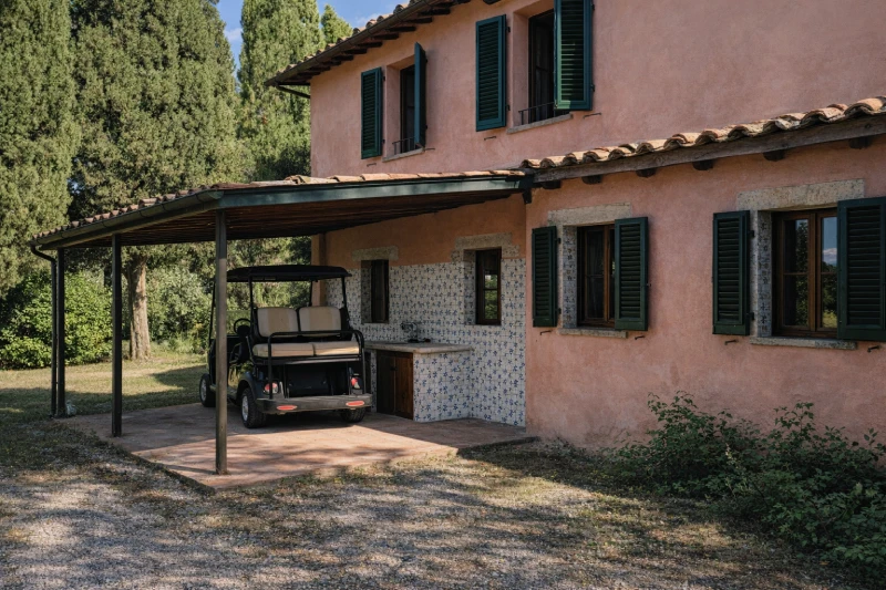 Villa exterior with covered patio, golf cart and rustic details surrounded by the Crete Senesi landscape - Villa San Bartolomeo, BZAR hotels in Tuscany
