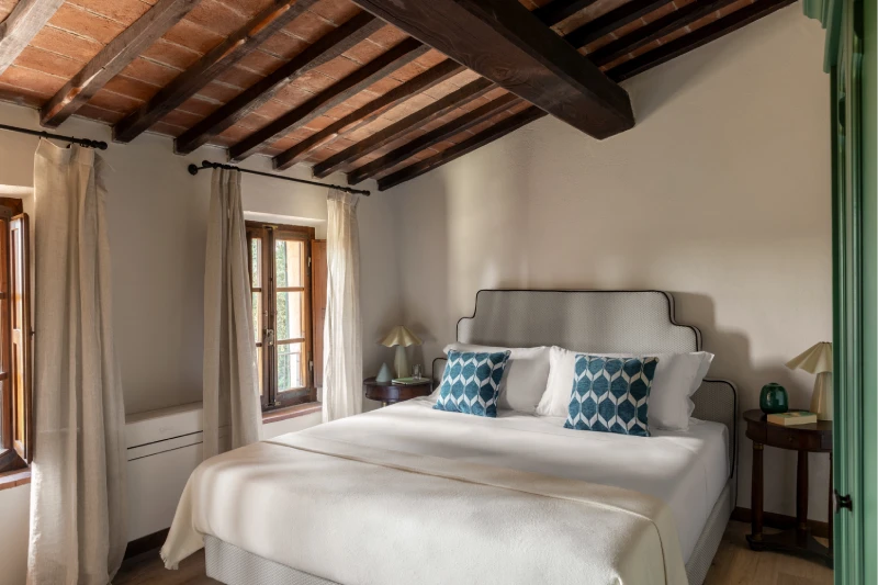Double bedroom at the Villa Annex Adults Only with terracotta beamed ceiling and blue cushions in the Crete Senesi - Castello di Leonina, BZAR hotels in Tuscany
