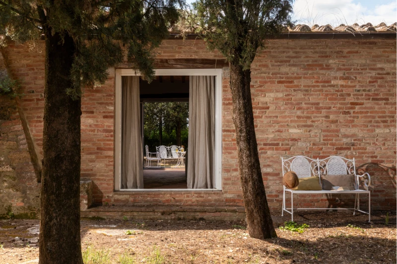 Exposed brick wall at the Villa Annex Adults Only with a glimpse of the outdoor terrace in the Crete Senesi near Asciano - Castello di Leonina, BZAR hotels in Tuscany